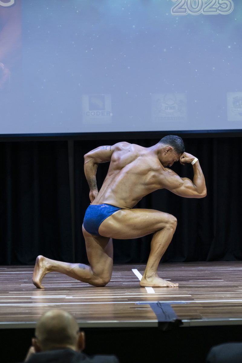 Kenny Coach posando en competencia de fisicoculturismo
