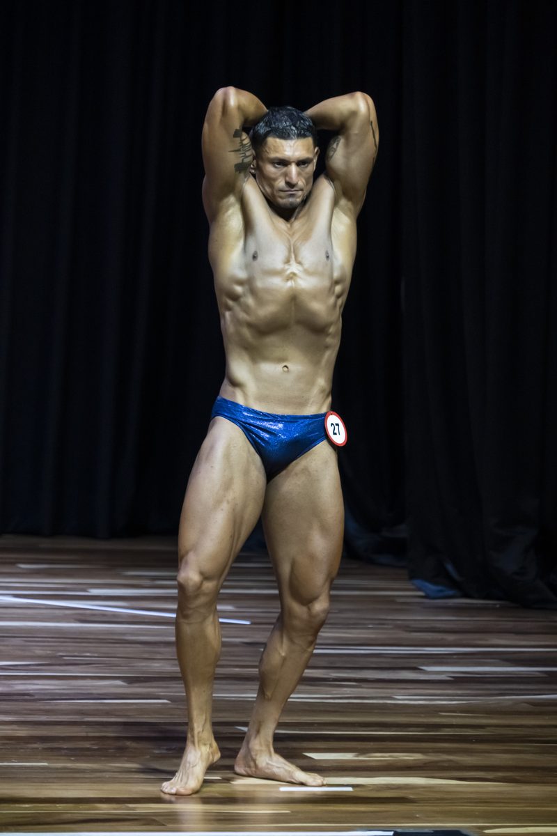 Kenny Coach posando en competencia de fisicoculturismo